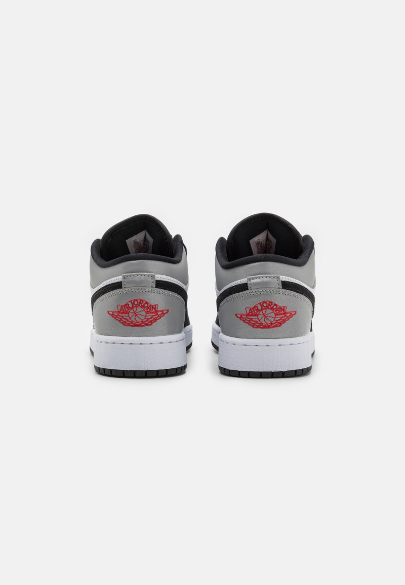 Baskets basses en cuir gris avec des accents noirs, dotées d'une semelle intermédiaire blanche et d'un logo rouge brodé au talon. Semelle extérieure texturée.
