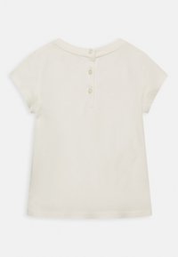 Camiseta de algodón blanca de manga corta con un escote redondo y cierre de tres botones en la parte trasera. Textura suave, dobladillo recto, diseño minimalista.