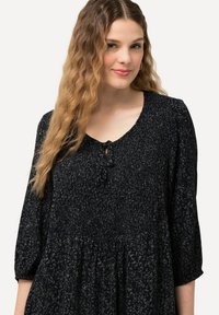 Vestito di un blu navy scuro con un pattern testurizzato, maniche a tre quarti e un collo rotondo che presenta un piccolo dettaglio con fiocco sul davanti.