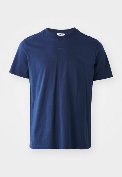 Tumši zili kokvilnas T-krekli ar īsām piedurknēm, apaļu kakla izgriezumu un smalku logotipa detaļu priekšā. Gluda tekstūra ar klasisku piegriezumu.