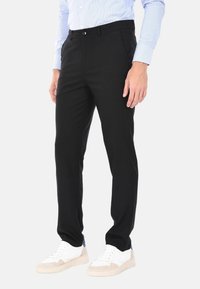 Pantaloni neri con una vestibilità sartoriale. Realizzati in un tessuto morbido, con tasche laterali, chiusura con un singolo bottone e una texture liscia.