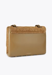 Tan handtas met een gewatteerde suède bovenkant en een gladde leren basis, voorzien van een gouden ketting schouderband en een reliëflogo aan de voorkant.