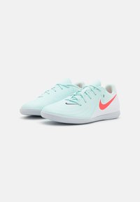 Világoskék sportcipők texturált felsőrésszel, fekete Nike logóval, rózsaszín kiemeléssel a saroknál és gumitalppal, amely mintázott tapadást biztosít.