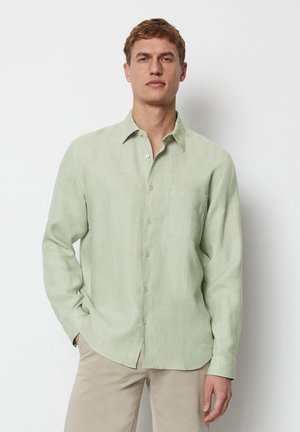 Light green button-up shirt made of linen with a chest pocket, long sleeves, and a curved hem. Features subtle texture and beige buttons.