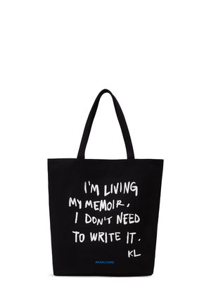 Black tote bag with two handles, white handwritten text saying "I'm living my memoir. I don't need to write it." and small blue hashtag #KARLCORE.