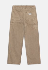 Pantaloni beige a gamba larga realizzati in cotone resistente, con due tasche posteriori e una tasca laterale cargo, dettagli cuciti e un'etichetta.