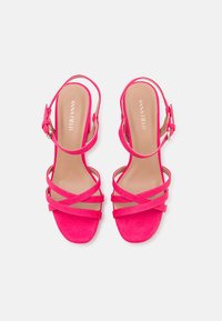 Sandales à talons hauts en daim rose avec des lanières croisées, une boucle à la cheville et un design à bout carré. Doublure intérieure lisse avec inscription de la marque.