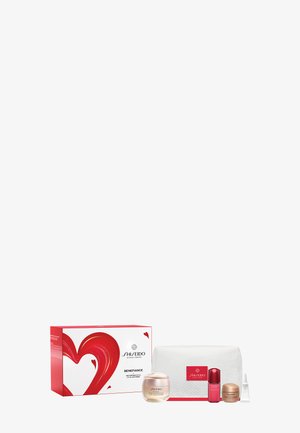 Ensemble de soins anti-rides Shiseido Benefiance comprenant un pot de crème, un flacon de sérum, un petit pot, un tube de traitement et une pochette matelassée blanche à côté d'une boîte rouge et blanche.