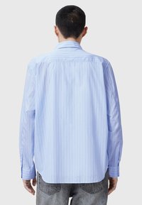 Lichtblauwe lange mouw shirt met verticale witte strepen, knoopsluiting kraag en een relaxte pasvorm, gemaakt van een gladde stof.