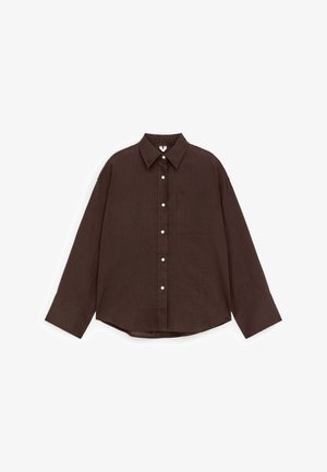 Chemise à manches longues marron foncé avec col pointu, poche poitrine avant et boutons blancs, posée à plat sur un fond blanc.