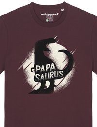 Bordeauxfarbenes T-Shirt mit einer schwarzen Dinosauriersilhouette und dem Text "PAPA SAURUS" in fetten, strukturierten weißen Buchstaben vor einem hellen, kreisförmigen Hintergrund.