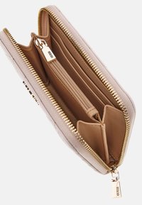 Portefeuille zippé rose avec un extérieur texturé, plusieurs emplacements pour cartes et une poche centrale zippée. Doté de quincaillerie dorée et d'une étiquette de marque.