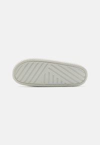Hvit sneaker såle med teksturert grep mønster, med horisontale og diagonale linjer. Rundede kanter og ribbenet omkrets for grep.