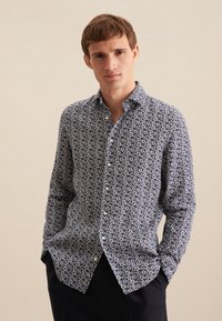 Camicia button-up a fiori navy con design aderente, motivi floreali bianchi, maniche lunghe e colletto classico. Texture del tessuto liscia.
