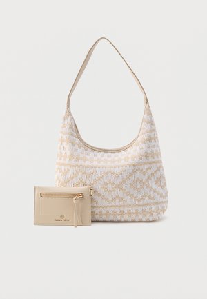 Sac à bandoulière à motifs beige et blanc avec un porte-cartes zippé beige assorti placé devant sur un fond blanc.
