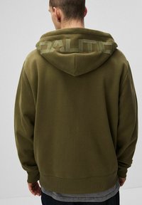 Oliwkowy hoodie z kapturem na sznurki, z wyraźnym haftowanym napisem "DALITIC" na plecach. Miękka tkanina i luźny krój.