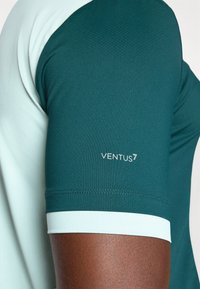 Īsām piedurknēm sporta krekls ar tumši zaļu korpusu, gaiši zaļām akcentiem, teksturētu audumu un "VENTUS7" logo uz piedurknes.