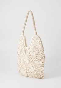 White, crocheted handbag with floral patterns, a textured surface, and two woven straps. U-shaped design with open top.