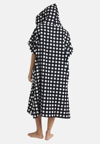 Black and white checkered hooded poncho made of soft fabric, featuring a loose fit and short sleeves, with notable grid pattern and logo tag.