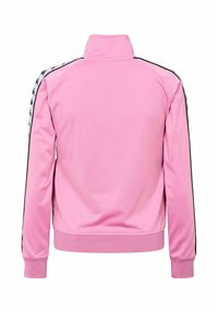 Jasnoróżowa długa bluza sportowa z wysokim kołnierzem i białymi paskami z czarnymi wzorami logo na ramionach i rękawach.