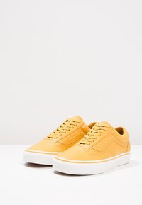 Gele leren sneakers met een lage schoenhoogte, witte rubberen zool, vetersluiting aan de voorkant en zijstikdetail. Gladde textuur.