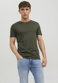 Oliven grønt bomulds t-shirt med rund hals og korte ærmer, parret med lyseblå denimjeans. Simpelt design, glat tekstur og tætsiddende pasform.