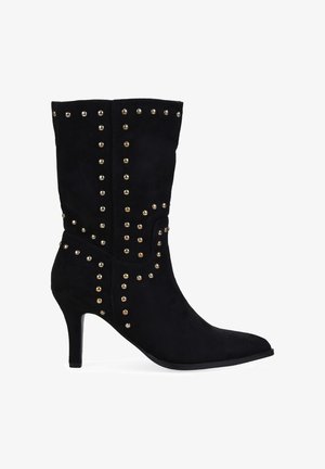 Botín negro de ante hasta el tobillo con puntera afilada, tacón de aguja y acentos dorados con tachuelas. Detalle de diseño vertical en la caña.