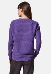Lila ribbad tröja med långa ärmar, rund halsringning och textilstruktur. Bakvy visar en avslappnad passform och lätt sänkt fåll.