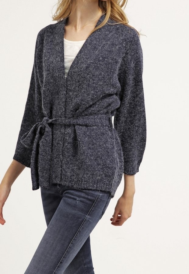 Marinblå stickad kofta med knyt i midjan, vida ärmar och V-ringning. Tyget har en mjuk, strukturerad yta.