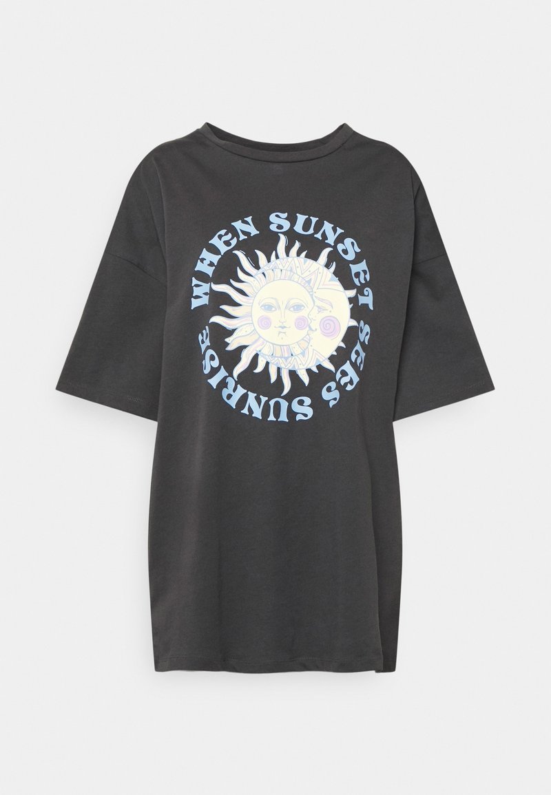 T-shirt noir oversize avec un graphisme pâle de soleil et de lune au centre, entouré d'un texte bleu disant "Quand le coucher du soleil voit le lever du soleil."