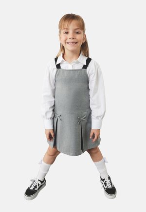 Szara sukienka z czarnymi ramiączkami, z plisowanym wykończeniem i detalami w postaci kokardek. Noszona na białej koszuli z długim rękawem. W połączeniu z czarnymi sneakerami i białymi skarpetkami.