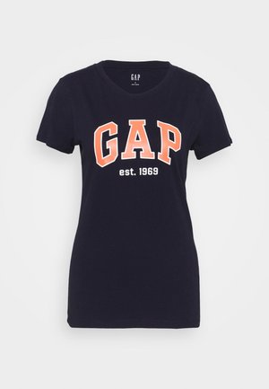 Granatowy t-shirt z krótkim rękawem i okrągłym dekoltem, z "GAP" dużymi pomarańczowymi literami i "est. 1969" białymi poniżej.