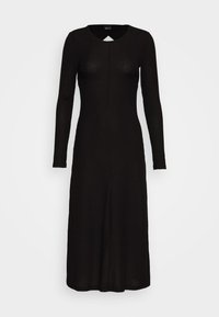 Svart ribbad stickad klänning med långa ärmar, rund halsringning och en nyckelhålsdetalj. Knälängd med en lätt utsvängning mot fållen.