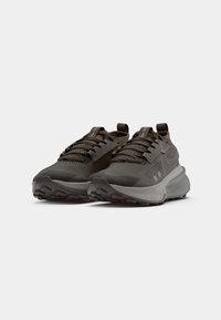 Chaussures de sport en gris foncé avec une tige texturée, des perforations respirantes, une languette rembourrée et une semelle extérieure en caoutchouc contrastante avec des crampons de traction.