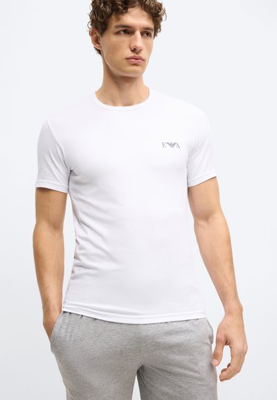 Balta īsroku T-krekls no gludas auduma ar apaļu kakla izgriezumu, kreisā krūšu daļā neliels logo.