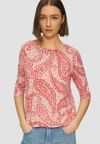 Lange mouwen roze top met een bloemenpatroon; lichte stof; ronde halslijn; losse pasvorm; heeft een abstract ontwerp in donkerdere tinten roze.