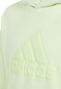 Sudadera verde claro con un logotipo de Adidas texturizado y en relieve en un tono a juego. Cuenta con un diseño clásico y una tela suave y lisa.