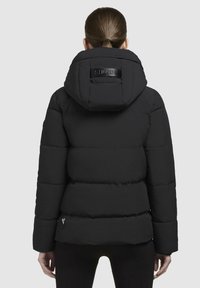 Veste puffer noire avec capuche, motif matelassé et patch en cuir au dos. Présente de grandes sections rembourrées et un design court.