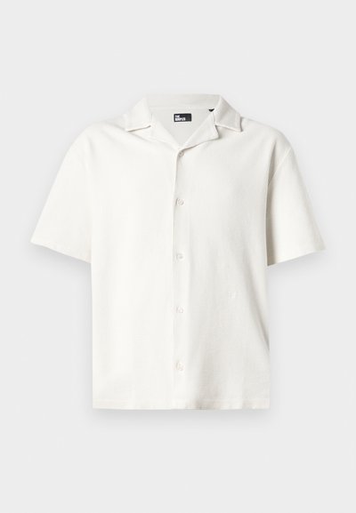Kurzärmliges, weißes Hemd aus strukturiertem Stoff mit einem Camp-Kragen und fünf Knöpfen, das eine lockere Passform und ein dezentes Muster aufweist.