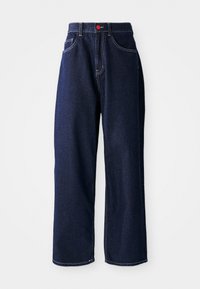 Mørkeblå vide jeans laget av denim, med oransje sømmer, en rød knapp og en klassisk fem-lomme design.