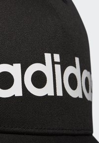 Cappello nero con un tessuto testurizzato e audace marchio "adidas" in bianco ben visibile sulla parte anteriore.