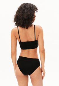 Zwarte naadloze beha en taillehoog slipje in een matte textuur. De beha heeft dunne bandjes en een gevormd ontwerp voor een soepele pasvorm.