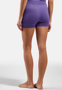 Shorts de sport violets avec une texture lisse, dotés d'une taille haute et d'un petit motif perforé près de la taille.