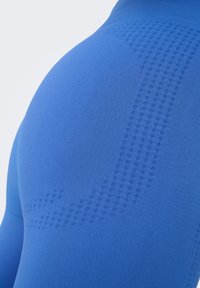 Gros plan d’un tissu bleu texturé avec un motif ponctué subtil formant un dessin courbe sur une surface courbée.