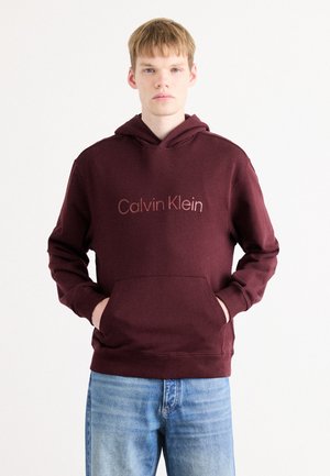 Maroon hoodie with a kangaroo pocket, featuring "Calvin Klein" logo in pink. Soft fabric, adjustable drawstring, ribbed cuffs and hem.