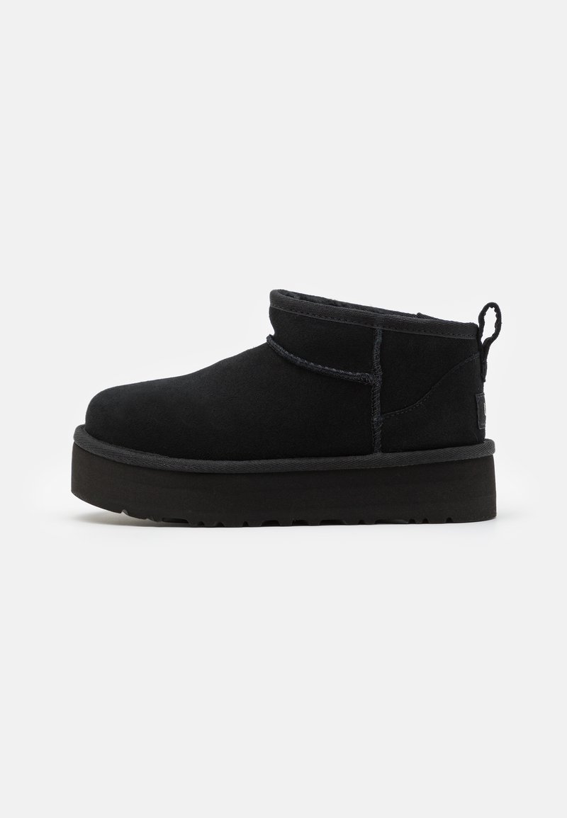 Botines de ante negro con punta redonda, cuello alto y tira de sujeción, que cuentan con una suela gruesa de goma negra texturizada.