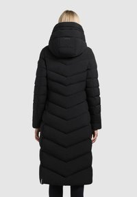 Cappotto imbottito nero con un motivo a zigzag, dotato di cappuccio e maniche lunghe. Il design è trapuntato, offrendo una silhouette elegante e affusolata.