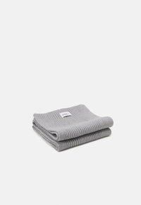 Écharpe en coton gris côtelé pliée avec une étiquette sur le dessus, présentant un motif texturé et une finition douce. Compacte et facile à ranger.