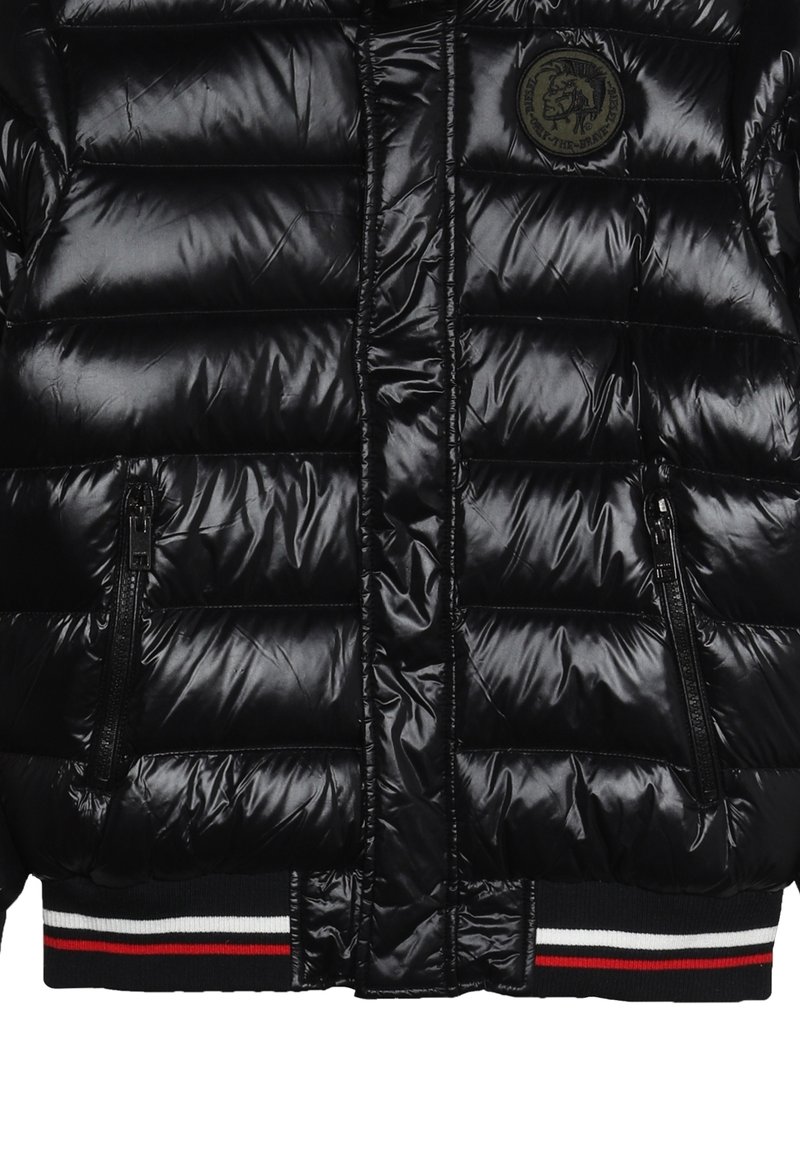 Doudoune noire avec une finition brillante, dotée de matelassage horizontal, de deux poches zippées et d'un ourlet côtelé avec des rayures rouges et blanches.
