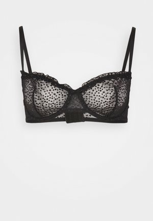 Black lace bralette with polka dot pattern. Features adjustable straps, scalloped trim, and a hook-and-eye closure at the back.